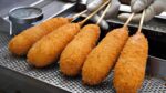 Cachorros-quentes de arroz alinhados no Seomun Market / cachorro-quente de queijo mussarela – comida de rua coreana
